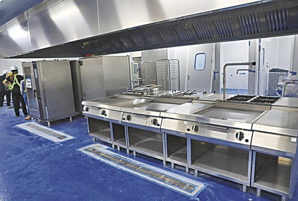 Varias planchas de cocina y un enorme extractor de humo y grasa, son parte de los equipos de esta cocina.