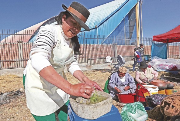 Una mujer indígena aimara prepara una llajua en un batán de piedra, durante el festival de la salsa picante, en El Alto (Bolivia).