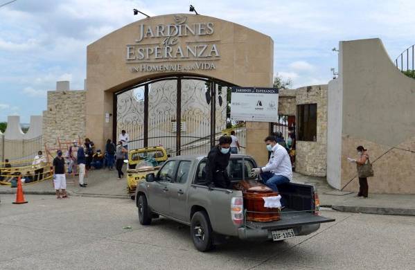 Personas con tapabocas transportan este miércoles el féretro de un fallecido, en un cementerio de Guayaquil (Ecuador).