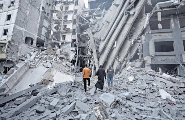 Palestinos inspeccionan los daños en los alrededores del edificio del Banco Nacional que fue destruido tras los ataques aéreos israelíes, en la ciudad de Gaza.