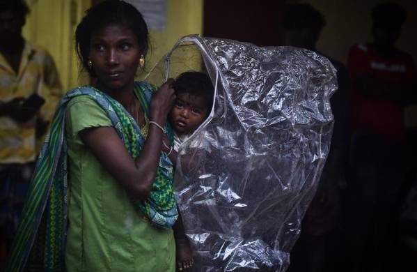 Una mujer y su hijo se cobijan de las fuertes lluvias, este viernes en Chennai (India).
