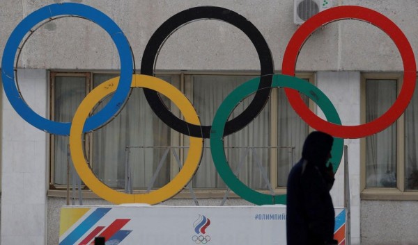Un hombre pasa delante de los anillos olímpicos que decoran el acceso a la sede del Comité Olímpico ruso en Moscú, Rusia.