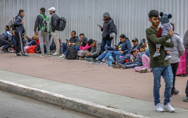 Migrantes esperan afuera de la garita internacional del Chaparral en la ciudad fronteriza de Tijuana (México).