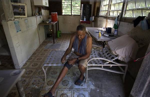 Fotografía del 13 de septiembre de 2022 donde aparece Félix Calderón mientras descansa en una parte de su casa afectada por el paso en el 2017 del huracán María por Canóvanas, Puerto Rico