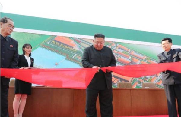 Kim Jong-Un corta el lazo de la construcción de la fábrica acompañado por su hermana y altos funcionarios del Gobierno.