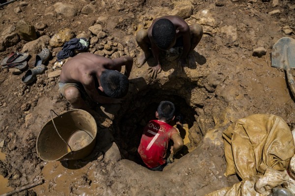 Niños mineros venezolanos trabajan cavando en una mina en busca de oro