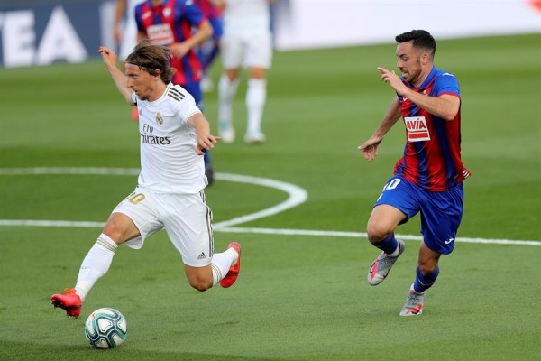 El centrocampista croata del Real Madrid Luka Modric (i) controla el balón ante el centrocampista del Eibar Edu Expósito en el partido de la jornada 28 de LaLiga