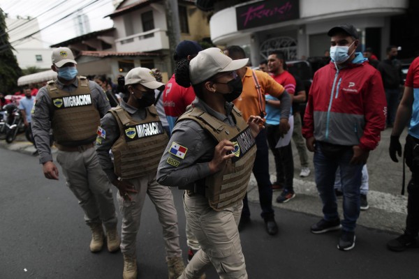 Agentes del Servicio Nacional de Migración (SNM) de Panamá custodian a motorizados de PedidosYa que participan en una manifestación
