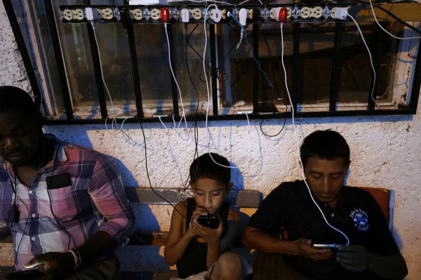En esta foto del 30 de julio del 2019, migrantes de África y Latinoamérica miran sus celulares en el albergue El Buen Pastor en Ciudad Juarez, México.