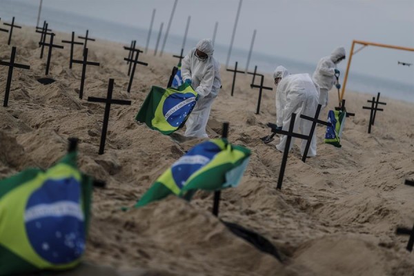Activistas colocan banderas de Brasil en las cruces y pancartas que leen Brasil, el país de las fosas.