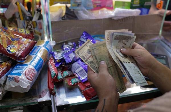 Un vendedor cuenta bolívares venezolanos y billetes de dólares estadounidenses en una tienda de comestibles en Caracas, en una imagen de archivo.