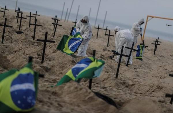 Activistas colocan banderas de Brasil en las cruces y pancartas que leen Brasil, el país de las fosas.