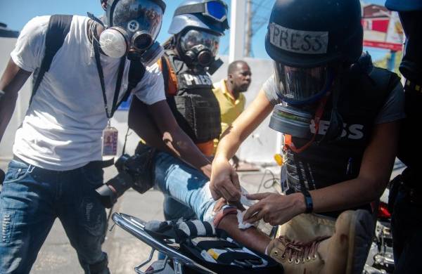Una periodista extranjera da prímeros auxilios a un fotoperiodista herido en una protesta en Puerto Príncipe (Haití).