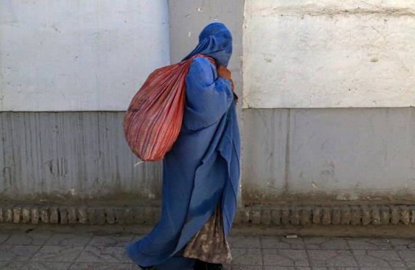 Una mujer con burka camina por una calle de Kabul, en la víspera del segundo aniversario de la victoria de los talibanes en Afganistán.