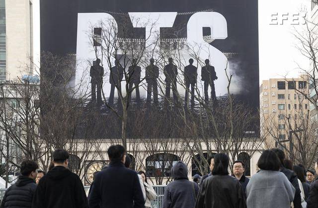 Seúl, 20/03/2026.- Varias personas caminan cerca del escenario principal para presenciar un concierto gratuito del grupo de K-pop BTS en la plaza Gwanghwamun de Seúl.