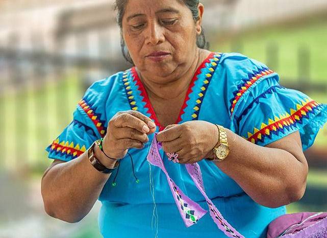 Artesanas confeccionan las naguas con diseños inspirados en la leyenda de la serpiente de siete cabezas.