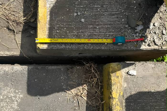 Evidencia de desplazamiento relativo entre segmentos de un puente (Puente de Tonosí) tras el terremoto. Se observa una desalineación lateral de los bordillos y una separación en la junta estructural, indicativas de una posible deformación asociada al movimiento sísmico. La cinta métrica se usa como referencia para documentar el desplazamiento observado en campo.