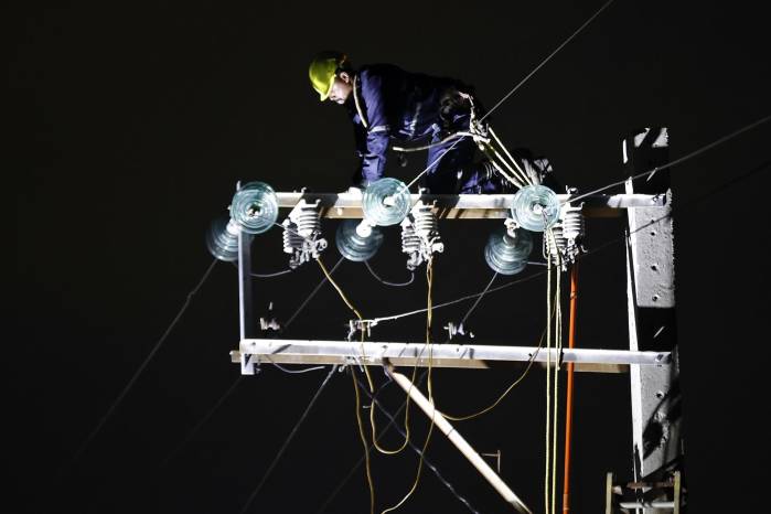 Fotografía de archivo de una persona trabajando en un poste de energía eléctrica.