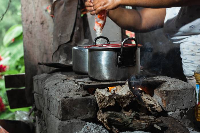 latin peasant cooking rice on an artisan stove made of bricks and ashes. stove lit with dry wood as fuel. traditional way of cooking on a colombian farm.