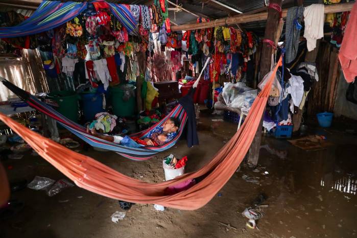 Con el paso de la lluvia, una mujer guna descansa en su hamaca después de poner sus enseres sobre palos o bolsa de plástico.