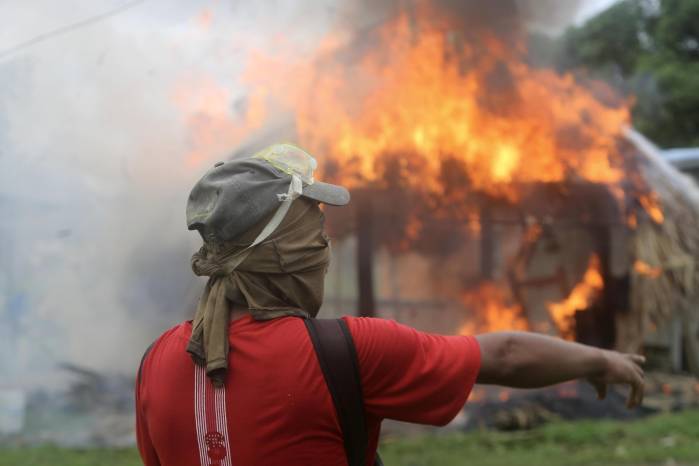 Una persona se enfrenta con integrantes de la Policía Nacional en una manifestación contra la reforma a la seguridad social este jueves, en Arimae.