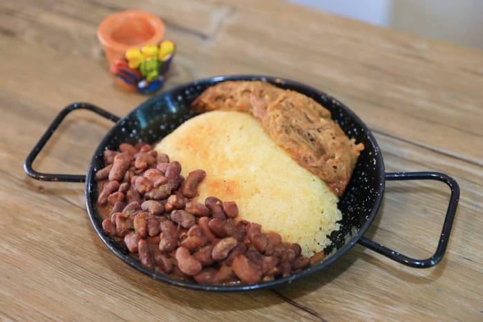 El plato insignia, el concolón, reinterpreta el pabellón criollo venezolano: carne mechada, frijoles y arroz tostado en el centro que aporta textura y sabor a hogar.