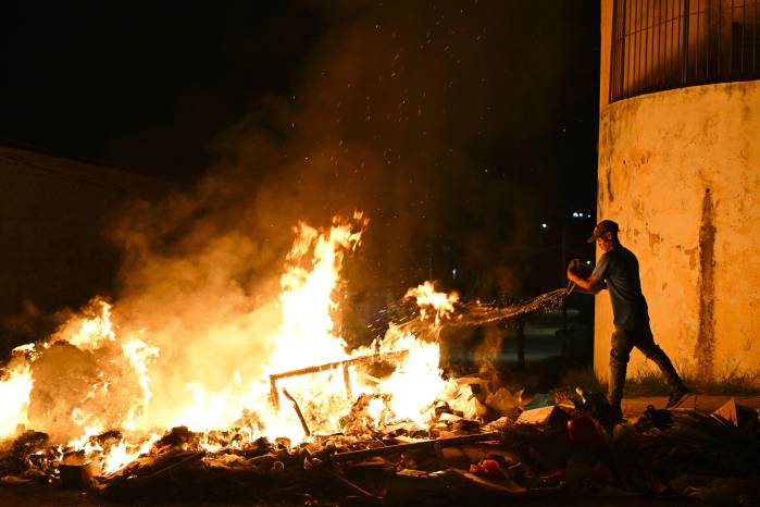 Un hombre arroja agua sobre un fuego encendido por manifestantes durante una protesta contra la falta de energía y los apagones en el barrio de Lawton, en La Habana.