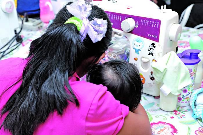 Joven con su bebé en clases de costura.