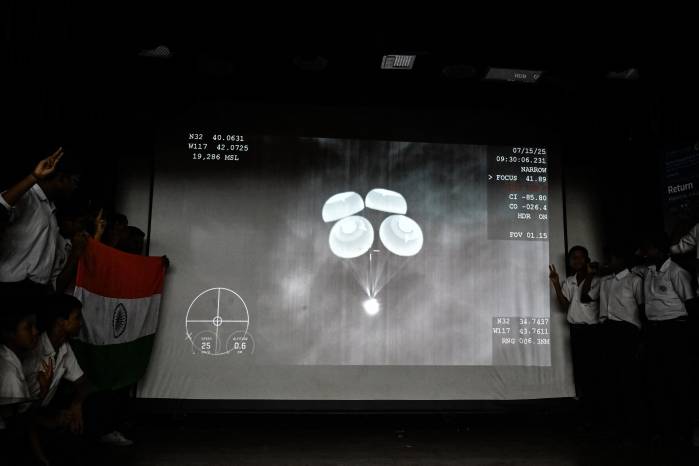 Estudiantes observan una transmisión en directo de la cápsula de SpaceX regresando a la Tierra desde la Estación Espacial Internacional, en un museo de ciencia en Calcuta.