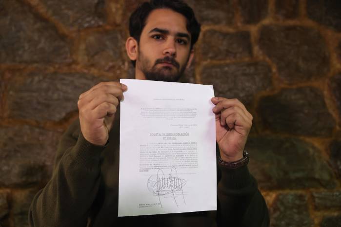 AME3507. CARACAS (VENEZUELA), 09/02/2026.- Ramón Guanipa, hijo del exdiputado antichavista Juan Pablo Guanipa, muestra la boleta de excarcelación de su padre durante una rueda de prensa este lunes, en Caracas (Venezuela). Ramón denunció que desconoce el paradero de su padre luego de que hombres no identificados se lo llevaran la noche del domingo y de que la Fiscalía anunciara que revocó la medida de excarcelación por un régimen de arresto domiciliario. EFE/ Miguel Gutiérrez