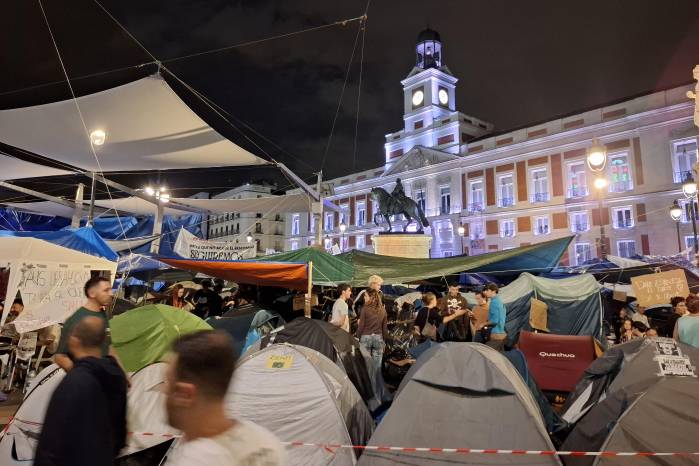 Los manifestantes soportan la lluvia mientras se mantienen en la Puerta del Sol.