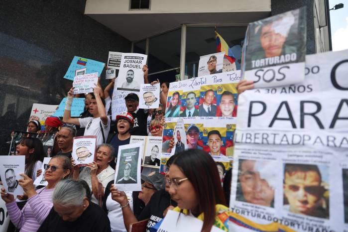 Fotografía de archivo de personas mientras sostienen carteles con imágenes de presos políticos en Caracas (Venezuela).
