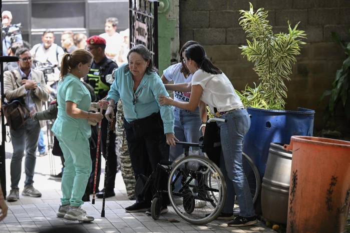 La madre de la líder opositora venezolana María Corina Machado, Corina Parisca Pérez (centro), es asistida en un centro de votación en Caracas durante las elecciones presidenciales del 28 de julio de 2024.