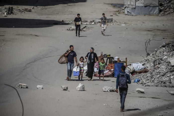 Los palestinos desplazados internamente se mueven con sus pertenencias antes de un ataque aéreo israelí en la ciudad de Gaza.