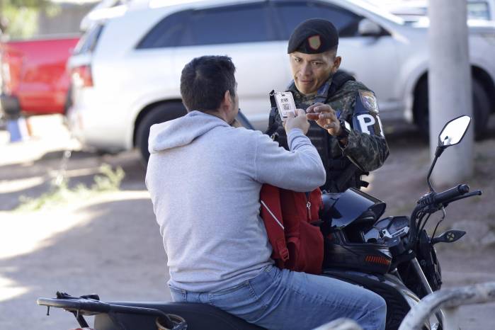 Un integrante de la Policía Militar de Honduras revisa el documento de un ciudadano este viernes, en Tegucigalpa (Honduras).