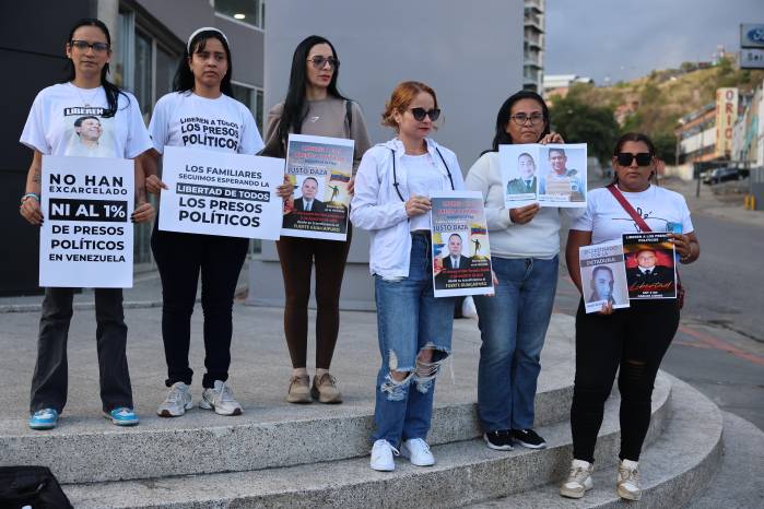 Familiares de presos políticos sostienen carteles afuera de El Helicoide este sábado, en Caracas.