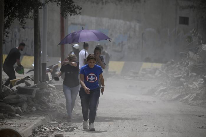 Residentes caminan por una calle llena de escombros mientras el polvo se cierne en el aire tras el terremoto en Catia La Mar, estado La Guaira, a unos 30 km al noroeste de Caracas, el 25 de junio de 2026.