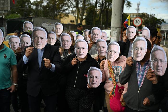 Partidarios del expresidente colombiano Álvaro Uribe portan máscaras con su rostro mientras esperan el veredicto de su juicio frente al Complejo Judicial de Paloquemao en Bogotá el 28 de julio de 2025.