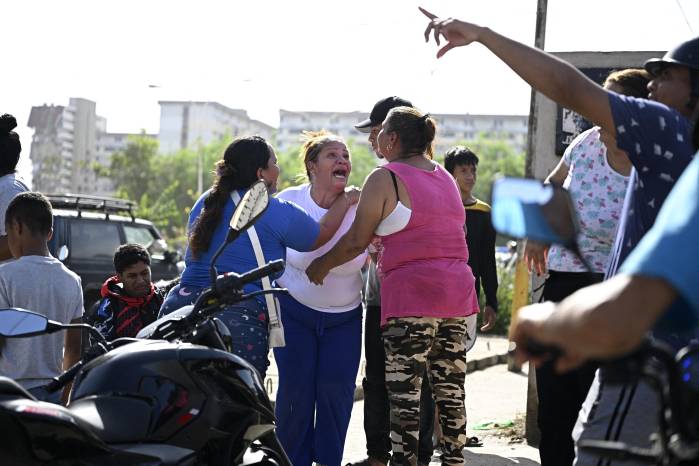 Varias personas reaccionan cerca de un edificio de apartamentos dañado tras un terremoto en Catia La Mar, estado La Guaira, a unos 30 km al noroeste de Caracas, el 25 de junio de 2026, mientras lloran la muerte de un familiar.
