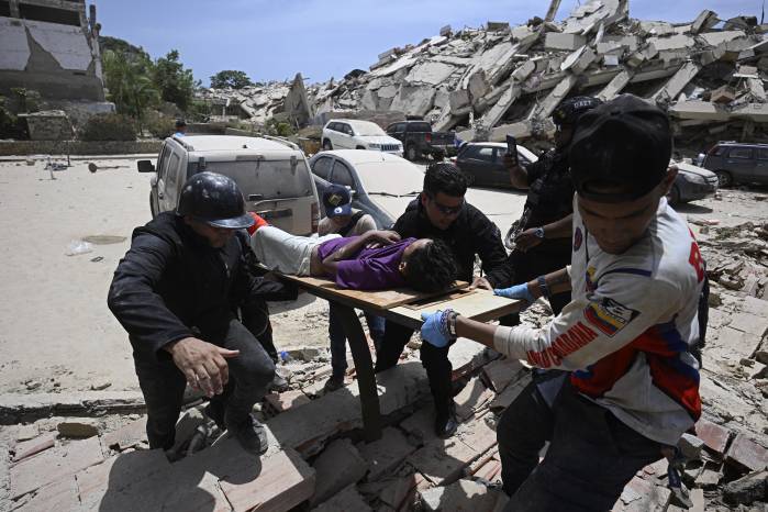 Rescatistas transportan a una persona herida en una camilla improvisada junto a una gran pila de escombros de un edificio derrumbado tras el terremoto en Los Corales, estado de La Guaira, a unos 38 km al noroeste de Caracas, el 25 de junio de 2026.