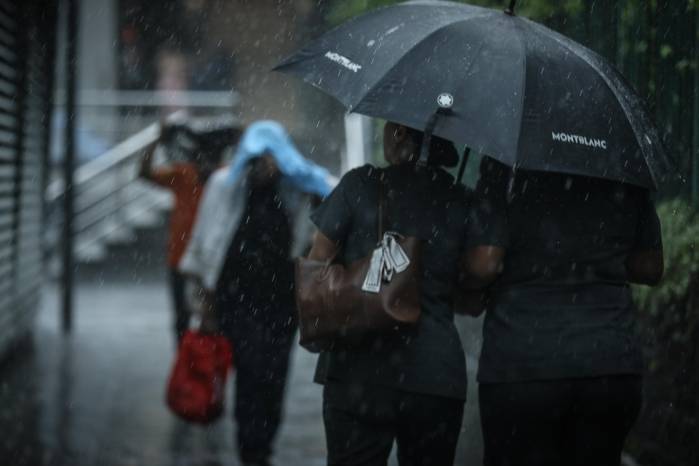 Personas se cubren de las lluvias que caen en la ciudad capital.