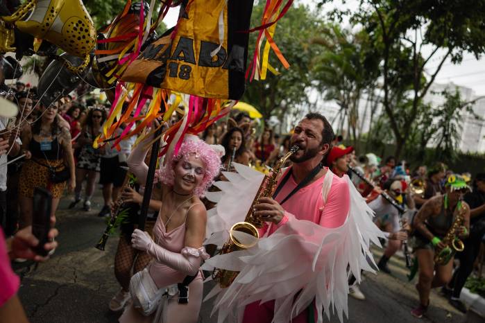 Personas participan en el desfile de la comparsa callejera Fanfarra Manada este sábado, en Sao Paulo (Brasil). Desde el amanecer, cientos de miles de personas se tomaron las calles de las principales ciudades de Brasil para celebrar el Carnaval, la fiesta más grande del país, en coloridas y ruidosas comparsas. EFE/ Isaac Fontana