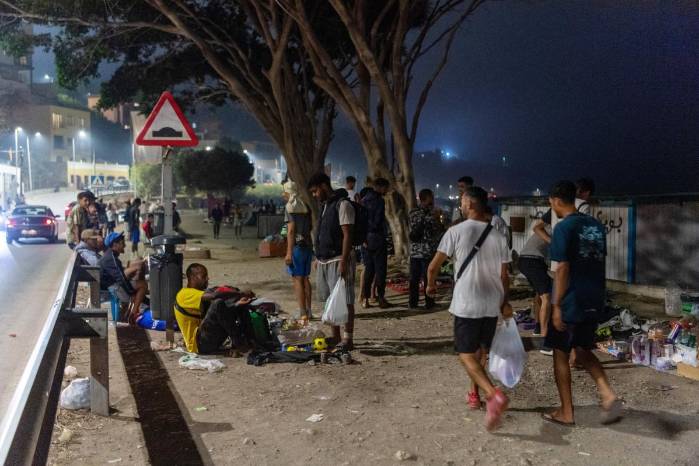 Los migrantes muestran ropa, alimentos y otros artículos colocados en el suelo para la venta mientras pasan la noche en la playa de El Tarajal, en Ceuta, el 1 de septiembre de 2026.