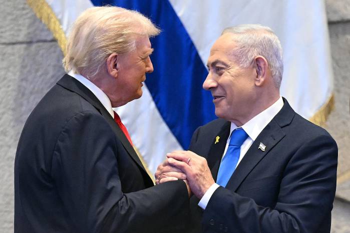 El presidente estadounidense Donald Trump (izq.) toma de la mano y conversa con el primer ministro israelí Benjamin Netanyahu en el Parlamento israelí.