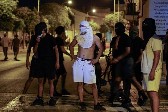 Residentes con la cabeza cubierta y mascarillas se congregan en la calle después de tres días de disturbios en Torre Pacheco, en el este de España, este 14 de julio.