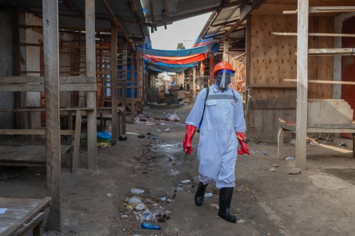 Un trabajador sanitario con equipo de protección desinfecta los puestos de un mercado de productos frescos en Bunia, provincia de Ituri, República Democrática del Congo, el pasado sábado.