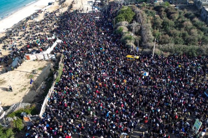 Una fotografía tomada por un dron muestra a familias palestinas esperando para regresar a la Franja de Gaza del Norte desde la Franja de Gaza del Sur, a lo largo de la carretera Rashid, al oeste del campamento de refugiados Nuseirat, en el centro de la Franja de Gaza, 26 de enero de 2025.
