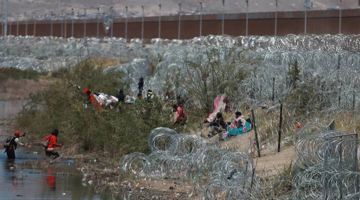 Migrantes llegan a una orilla del Río Bravo sembrada con alambre de púas en Cudad Juárez, Chihuahua (México).