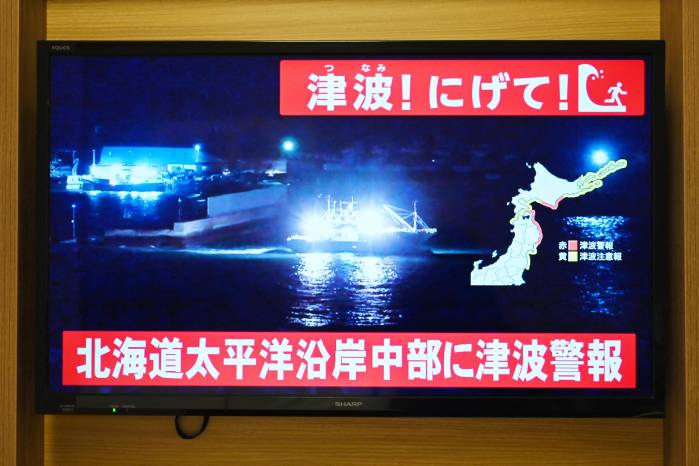 Se emite una alerta de tsunami mientras en una televisión en Sapporo, en la prefectura de Hokkaido, al norte de Japón, se muestra en directo la imagen de un barco saliendo de un puerto costero el 8 de diciembre de 2025.