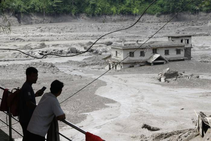 Varias personas observan cómo las aguas de la inundación arrasan Trishuli Bazar tras una crecida repentina, en el distrito de Nuwakot, Nepal.
